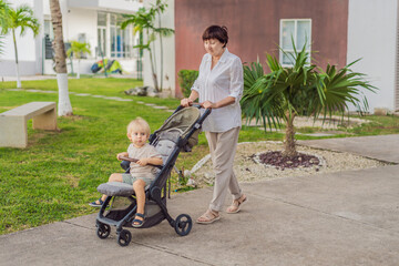 Unaltered senior woman walking outdoors with her grandchild in a stroller, enjoying a peaceful family moment in the fresh air. Concept of family bonding, active aging, caregiving, wellbeing and