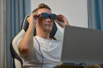 Man Putting On Wearable AR XR Smart Glasses While Using Laptop
