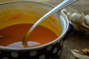 Creamy Homemade Pumpkin Soup in a vintage pot with a ladle. Closeup view. 