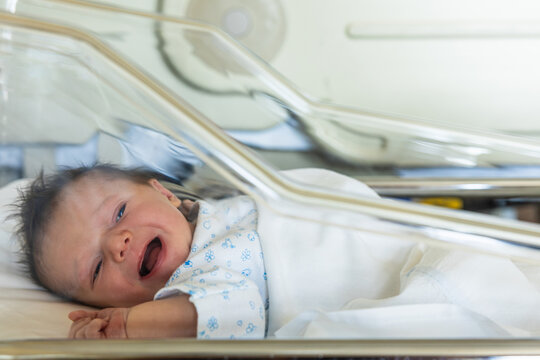 Newborn baby crying feeling uncomfortable in a hospital bassinet
