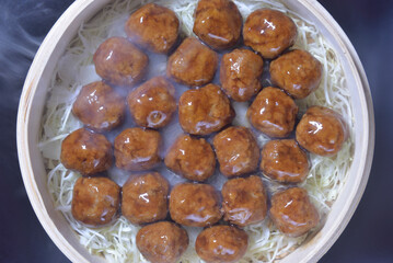湯気の立ち昇る蒸籠で肉団子を蒸す