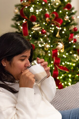 Woman holding Cup of Hot Beverage With Christmas Lights in Background Cozy Moment With Warm Drink in Front of Christmas Tree