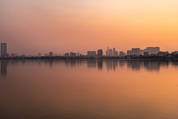 Obraz premium Hazy Sunset Over City Skyline and Lake