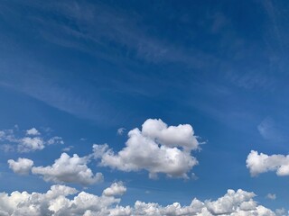 A vast expanse of brilliant blue sky scattered with soft, billowing white cumulus clouds on a clear...