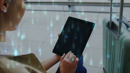 Woman tapping tablet at airport gate, tap causing binary digits overlay near suitcase while waiting