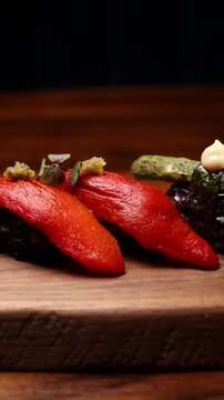Luxury gourmet sushi platter with mango, avocado and black rice on rustic wooden board, smooth rightward camera movement at medium speed in elegant fine dining setting