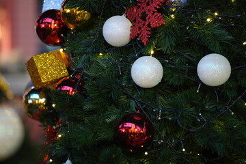 a Christmas tree topped with a golden star and decorated with warm golden lights. In the background, a larger Christmas tree glows brightly with sparkling lights, creating a warm and festive holiday