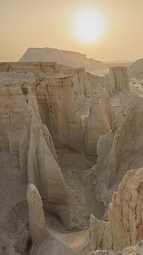 Aerial view of the sun rising over the stark, eroded landscape of the Lut Desert, casting long shadows across the unique yardangs and cliffs, Shahdad, Kerman Province, Iran.