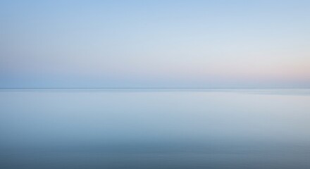 Obraz premium A serene, pale blue expanse of water meeting a soft, pastel sky