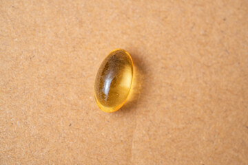 Omega 3 translucent capsule tablet on a solid surface.