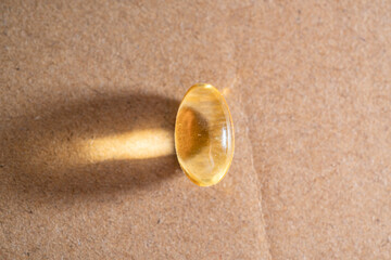 Omega 3 translucent capsule tablet on a solid surface.