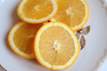 Slices of orange on a plate and a white background and a vintage plate. Fruit and good nutrition. Orange and sources of vitamins. Orange background.