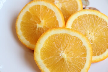 Slices of orange on a plate and a white background. Fruit and good nutrition. Orange and sources of vitamins. Orange background.