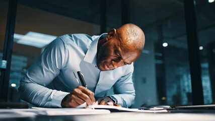 Intense African American businessman sweating while working late, diligently writing notes at his office desk. - Powered by Adobe