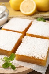 Tasty lemon bars with powdered sugar and mint on table, closeup