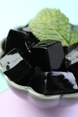 Tasty herbal jelly and mint leaf on color background, closeup