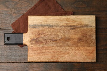 One cutting board and napkin on wooden table, top view. Space for text