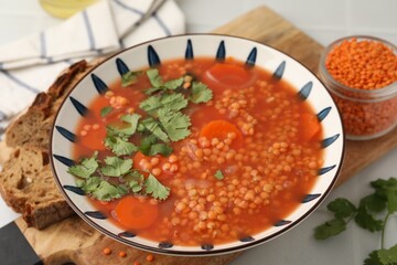 Tasty lentil soup in bowl served on light table, closeup