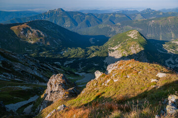 View of rugged, sun-kissed mountain peaks and lush green valleys under a clear sky creating a scenic landscape, Bobrovec, Zilina Region, Slovakia.