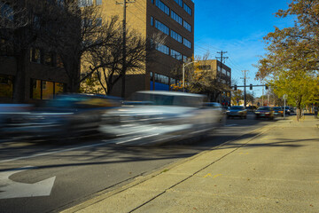 Vehicular traffic on busy city street, vehicles are blurred to emphasized motion. 
