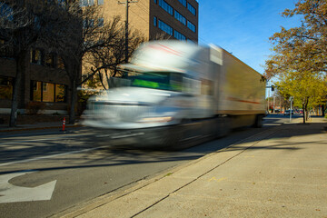 Vehicular traffic on busy city street, vehicles are blurred to emphasized motion. 