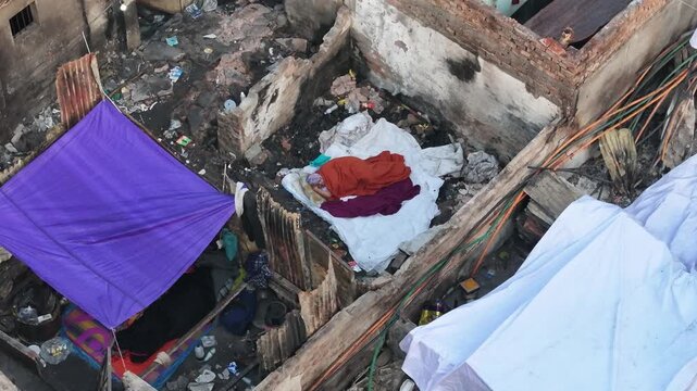 Dhaka, Bangladesh - 28 November 2025: Aerial view of buildings damaged with purple and white tarps contrasting with the gray rubble and exposed brick.
