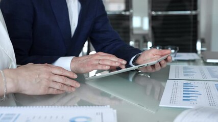 Business partners collaborating on a digital tablet, analyzing financial data and reports during a corporate meeting in a modern office, planning strategies for growth - Powered by Adobe