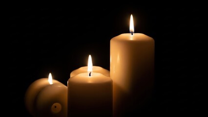 Three lit white pillar candles glowing softly in the dark, creating a warm and solemn atmosphere for remembrance or meditation