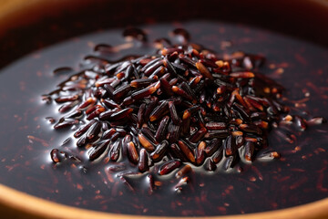 Black rice and rice water are in a wooden bowl. Close-up of black rice and rice water.