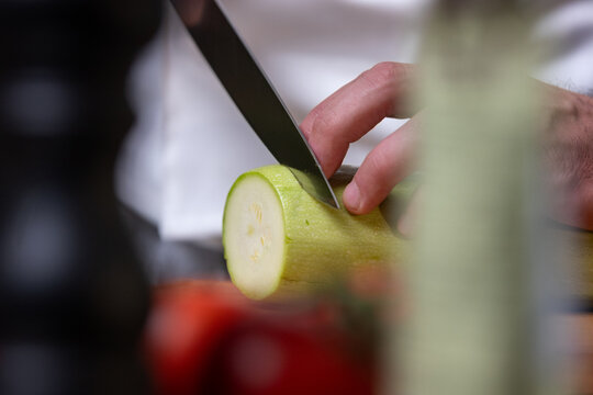 Chef Slicing Zucchini in Kitchen