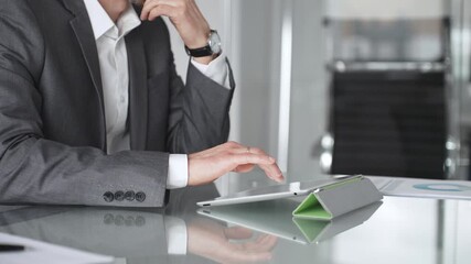 Businessman in a modern office setup, focusing intently on a tablet screen while engaging in strategic thinking, analyzing data, and preparing for an important corporate meeting or presentation