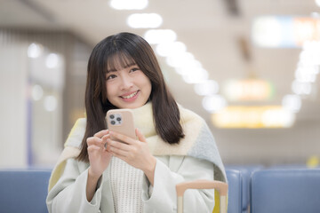 空港や駅のターミナルでスマホを操作する女性