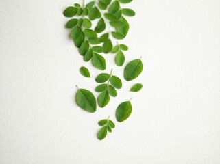 Close-up shot of fresh green moringa leaves scattered on a white surface, showcasing natural beauty.