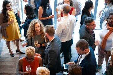 Diverse group at a social event, mingling and chatting. People holding drinks, engaging in...