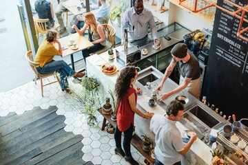 A vibrant cafe scene featuring diverse individuals. A baristra serves coffee to a customer, while others enjoy drinks. The cafe atmosphere is lively and welcoming, perfect for socializing.