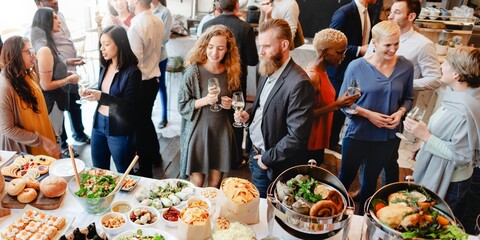 Diverse group at a social event, enjoying food and drinks. Men and women of various ethnicities...