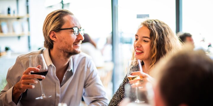 A group of people enjoying wine at a social gathering. Smiling and chatting, they hold wine glasses, creating a lively and friendly atmosphere. Friends at festive lunch with wine.