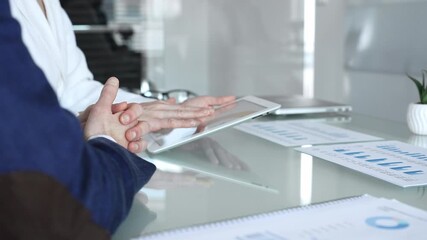 Business partners collaborating on a digital tablet, analyzing financial data and reports during a corporate meeting in a modern office, planning strategies for growth - Powered by Adobe