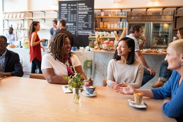 People socializing in a cozy cafe. Diverse group enjoying coffee and conversation. Relaxed atmosphere with friends in a welcoming cafe setting. Diverse people at a cafe.