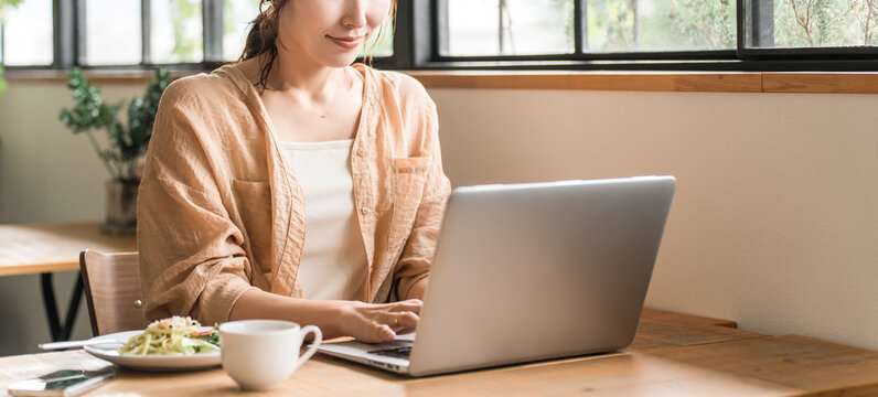 A woman teleworking while having lunch at a cafe
