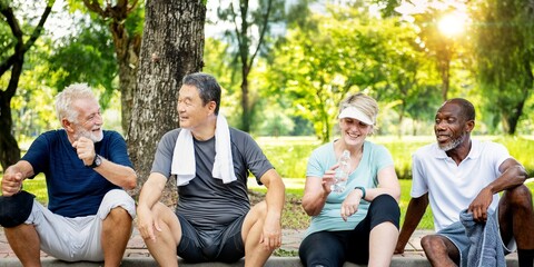 Group of diverse senior people sit and talk at park, happy group. Diverse senior friends sitting, enjoy park exercise. Happy smiling seniors, active outdoors lifestyle, diverse senior group