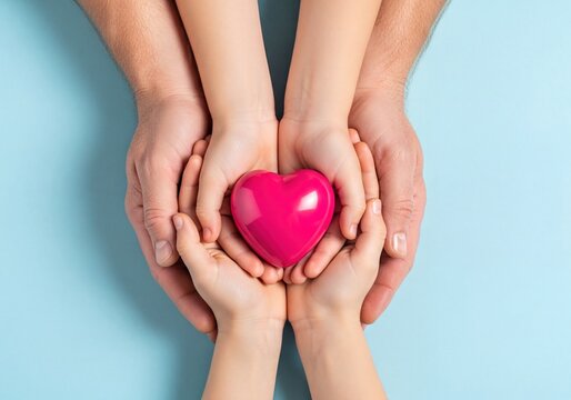 Pink heart held gently in cupped hands of parent and child symbolizing love