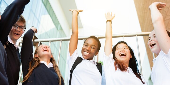 Group of diverse students celebrating. Happy diverse students with arms raised celebrate and teamwork. School boys and girls raise hands joyful. Smiling diverse student friends raise hands celebrate