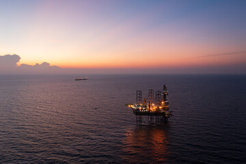 Fototapeta premium Aerial view of offshore jack up rig and offshore platform during sunset for oil and gas exploration and production.