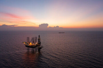Aerial view of offshore jack up rig and offshore platform during sunset for oil and gas exploration and production.