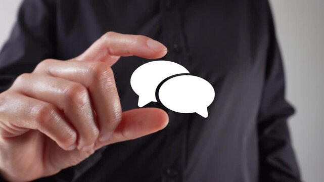 Holding conversations. Close-up of a woman's hands holding a speech bubble icon between her two fingers.