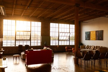 Spacious loft with large windows, warm lighting, and modern furniture. Loft features exposed brick, cozy seating, and a stylish, open atmosphere. Urban loft style home interior in studio with couch.