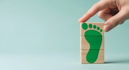 Hand placing wooden block with green footprint symbol on light blue
