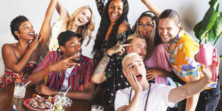 Group of diverse friends having fun, taking selfies. Smiling, laughing, enjoying time together. Diverse group, diverse fun, diverse smiles. Friends celebrating at party.