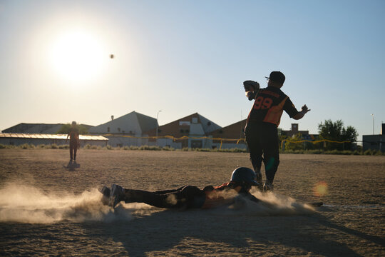 Baseball player sliding headfirst into base, creating a cloud of dust during game - Powered by Adobe